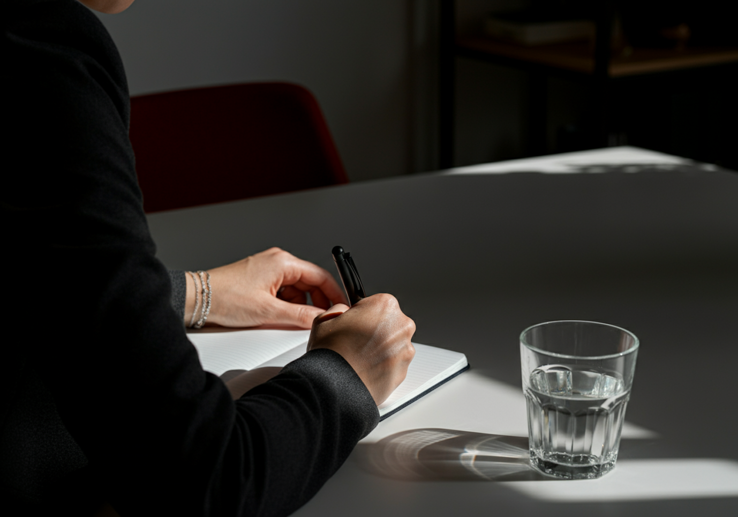 A person writing in a notebook, symbolizing the process of self-reflection and using a thought record as a CBT technique.