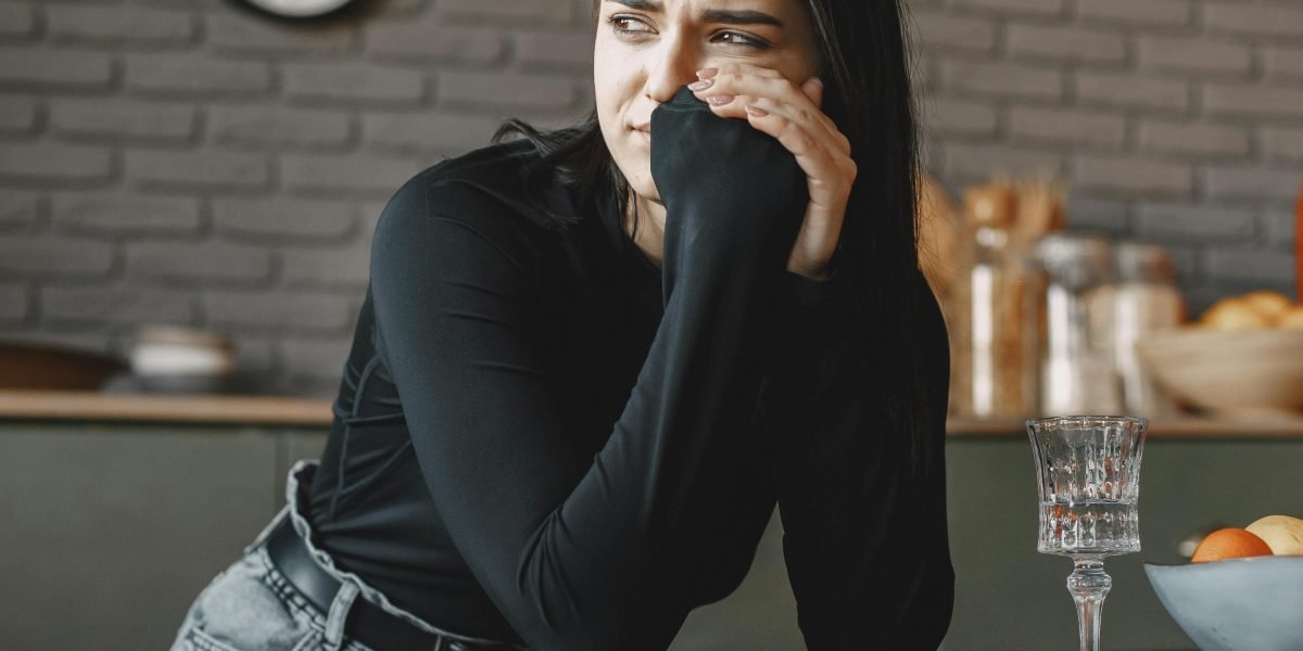 A woman sits alone, deep in thought, reflecting the internal struggle of relationship anxiety.