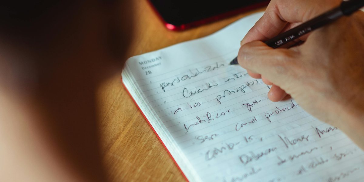 An individual thoughtfully writing in a journal, reflecting on progress and building confidence through self-help strategies.
