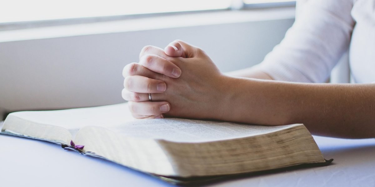 A person engaging in a meditative practice, combining spiritual focus with a physical gesture like placing a hand on the heart.