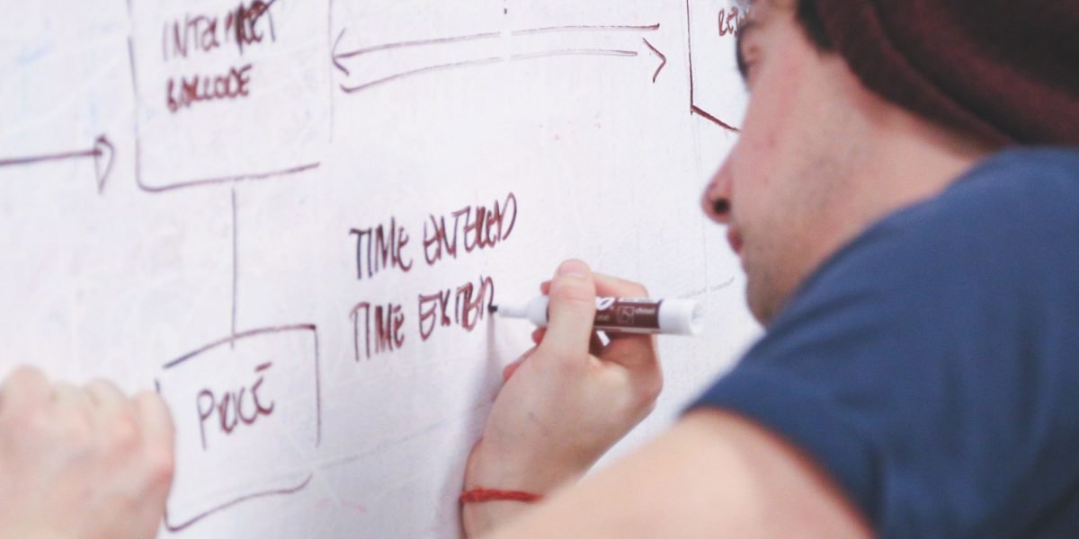 A person actively outlining thoughts or strategies on a whiteboard, reflecting the structured approach of CBT.